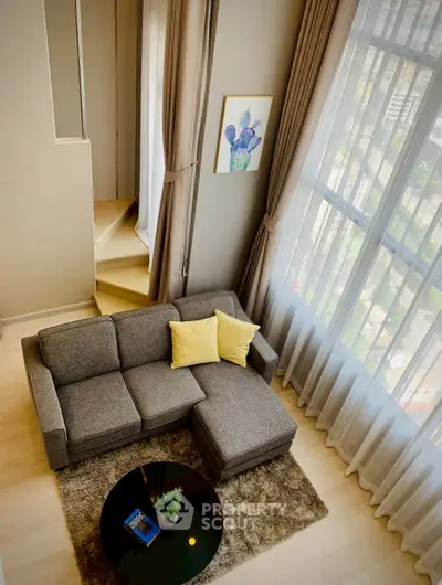 Stylish modern living room with high ceilings and large windows offering city views.