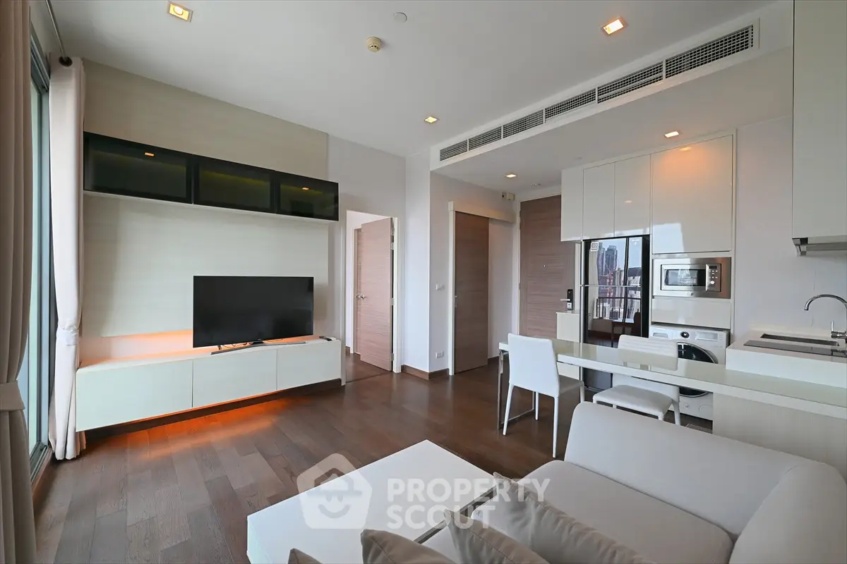 Modern living room with sleek furniture and open kitchen layout in a stylish apartment.