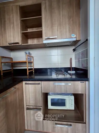 Modern kitchen with wooden cabinets and built-in microwave, featuring a sleek gas stove and ample storage space.