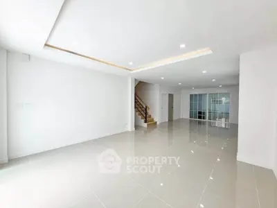 Spacious modern living room with glossy tiled floors and elegant staircase