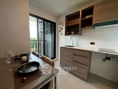 Modern kitchen with open layout and balcony view, featuring sleek cabinetry and dining area.