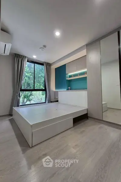 Modern bedroom with built-in storage and large window overlooking greenery.