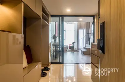 Modern interior hallway leading to a stylish living room with glass partition and elegant decor.