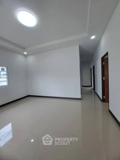 Spacious empty room with modern ceiling lights and glossy tiled floor, perfect for customization.