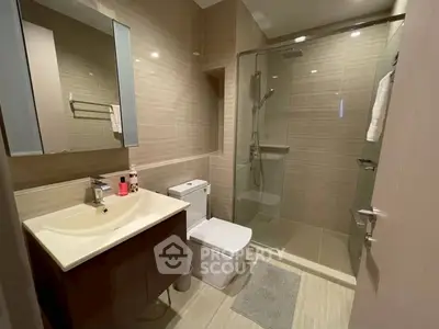 Modern bathroom with glass shower and sleek vanity in upscale apartment.