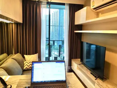 Modern living room with city view, featuring sleek furniture and a large TV.