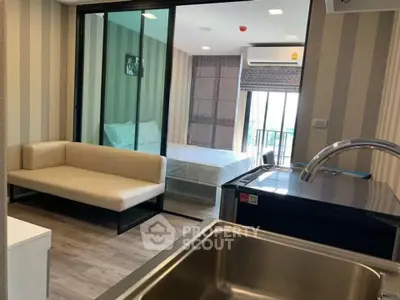 Modern studio apartment with open layout, featuring a cozy living area and a sleek kitchen.