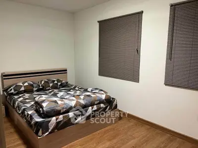 Cozy bedroom with modern geometric bedding and wooden flooring, perfect for restful nights.