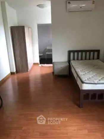 Spacious bedroom with wooden flooring and modern furnishings in a cozy apartment.