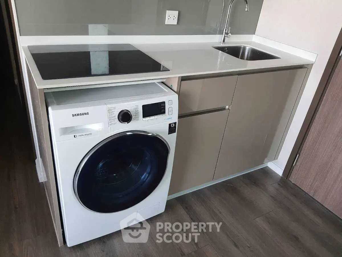 Modern kitchen with sleek cabinetry, built-in washing machine, and electric cooktop.