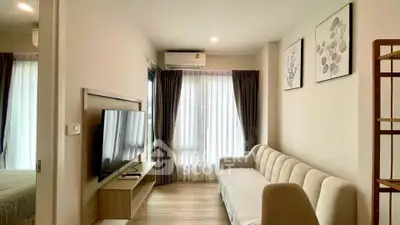 Modern living room with stylish decor, large TV, and cozy sofa in a bright apartment.
