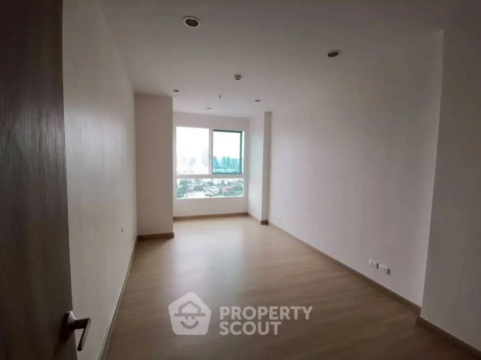Spacious empty room with large window and city view, perfect for customization.