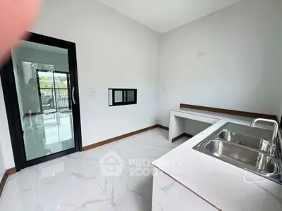 Modern kitchen with sleek countertops and stainless steel sink, featuring a bright open layout.
