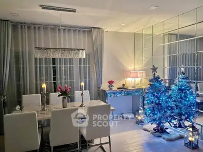 Elegant dining room with festive decor and mirrored wall, featuring a chic chandelier and holiday tree.