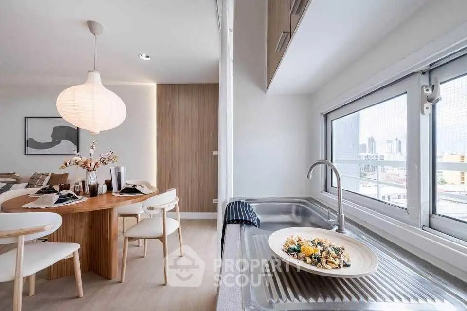 Modern dining area with stylish kitchen and city view, featuring elegant decor and natural light.
