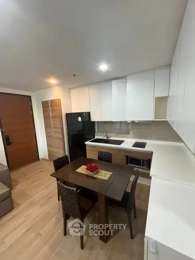 Modern kitchen with sleek cabinetry and dining area in a stylish apartment.