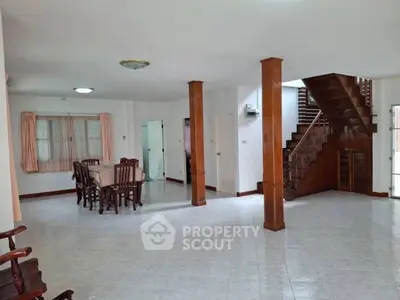 Spacious open-plan living area with dining set and wooden staircase