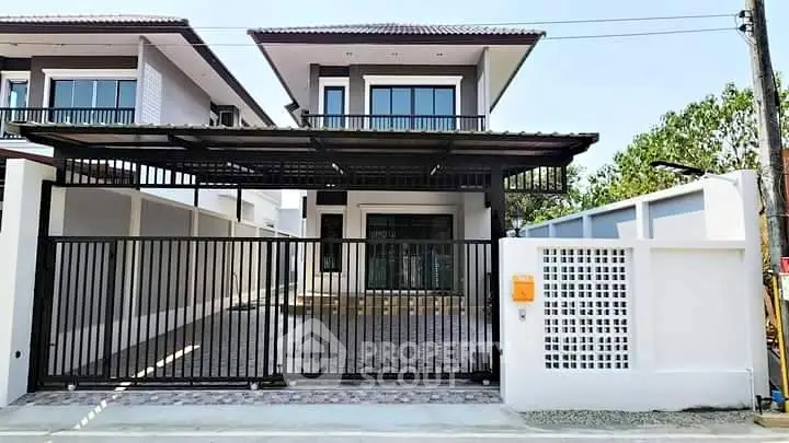 Modern two-story house with gated driveway and contemporary design.