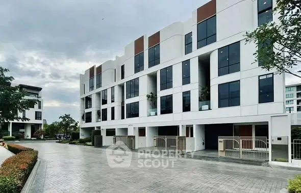 Modern multi-story residential building with sleek design and spacious driveways.