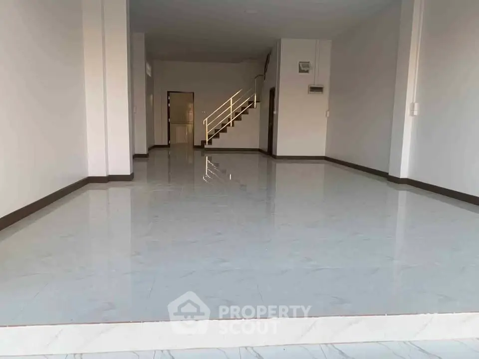 Spacious open-plan interior with glossy tiled floors and staircase, ideal for customization.