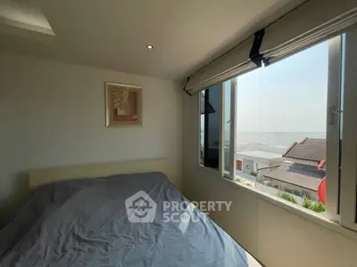 Cozy bedroom with large window offering stunning city view and natural light.