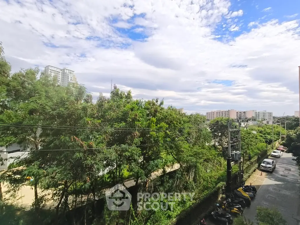 Scenic urban view with lush greenery and distant buildings under a vibrant sky.