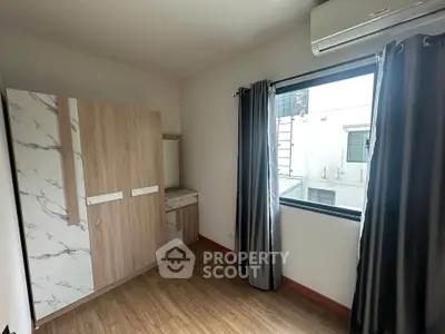Spacious bedroom with modern wardrobe and large window offering natural light.