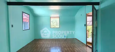 Spacious empty room with wooden flooring and large windows offering natural light.