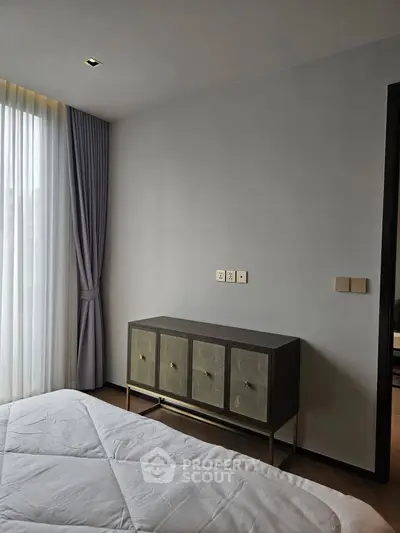 Modern bedroom with stylish cabinet and natural light through large window.
