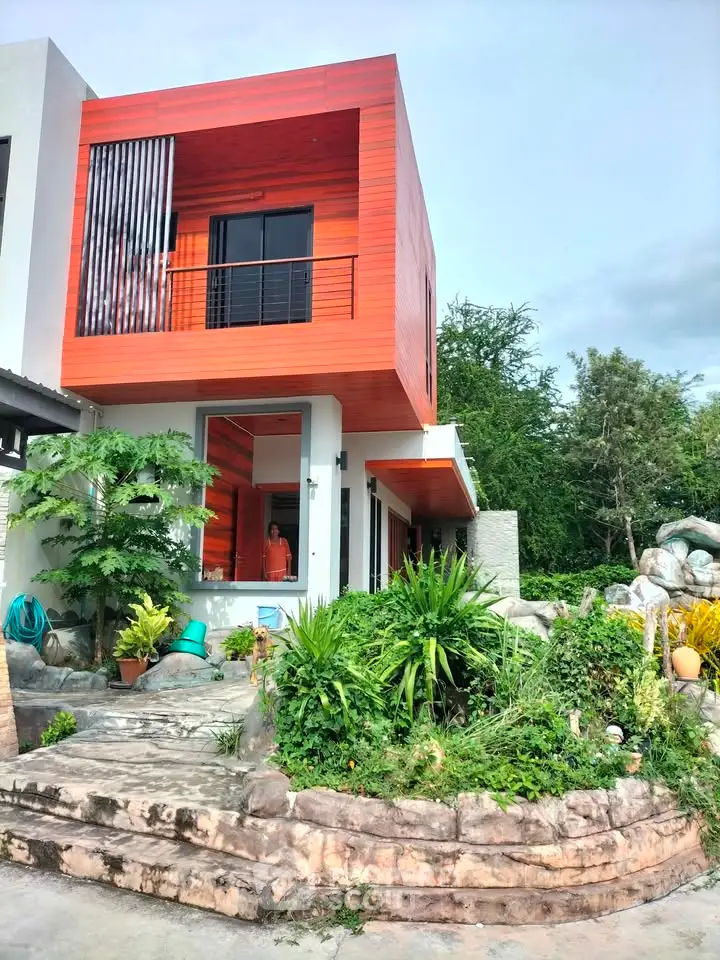 Modern two-story house with unique architectural design and lush garden landscape.