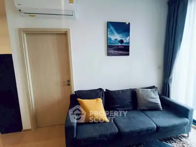 Modern living room with stylish sofa and wall art, featuring natural light from large window.