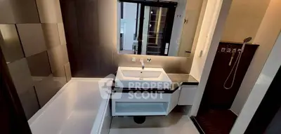 Modern bathroom with sleek design, featuring a bathtub and stylish fixtures.