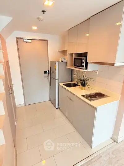 Modern compact kitchen with sleek cabinets and appliances in a cozy apartment.