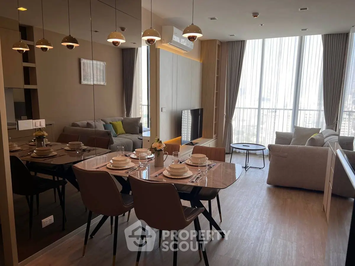 Modern living room with dining area, featuring stylish furniture and large windows with city view.