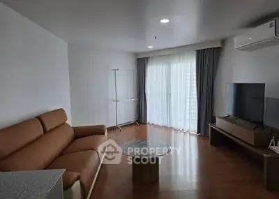 Spacious modern living room with leather sofa and large TV, ideal for relaxation.