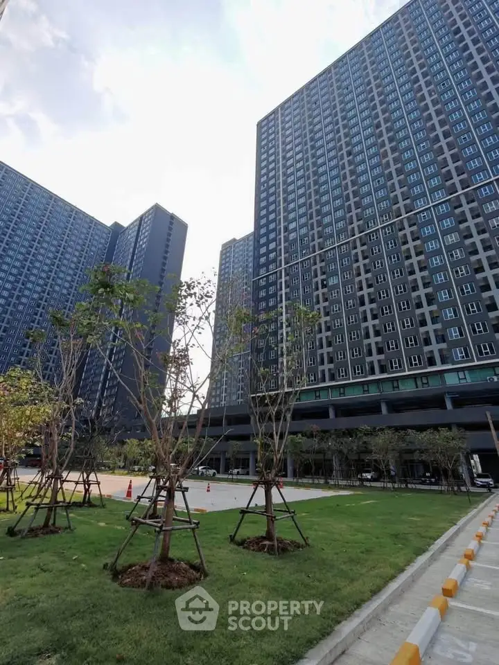 Modern high-rise residential buildings with landscaped garden and clear sky.