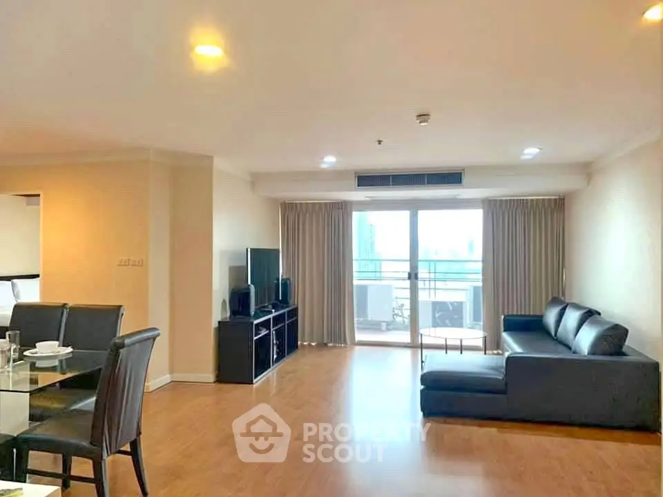 Spacious living room with modern furniture and balcony view in a high-rise apartment.