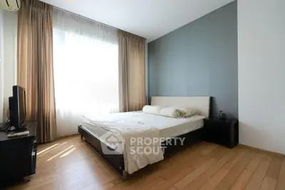 Spacious bedroom with modern decor and natural light in a stylish apartment.