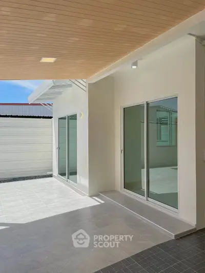 Modern patio with sliding glass doors and covered ceiling, perfect for outdoor relaxation.