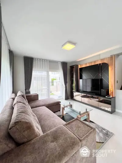 Spacious modern living room with plush sectional sofa and large TV, featuring elegant curtains and sleek decor.