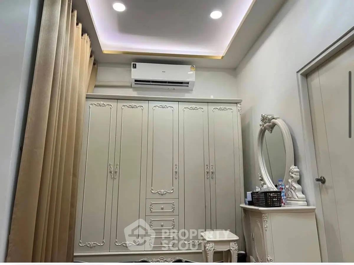 Elegant bedroom with ornate wardrobe and vanity, featuring soft lighting and neutral tones.