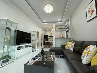 Modern living room with sleek decor, glass display cabinets, and a cozy black leather sofa.