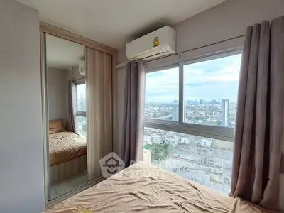 Cozy bedroom with mirrored closet and city view from window.