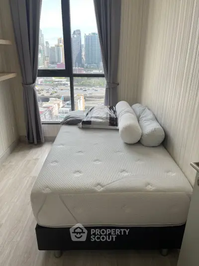 Cozy bedroom with city view, featuring a comfortable bed and large window for natural light.