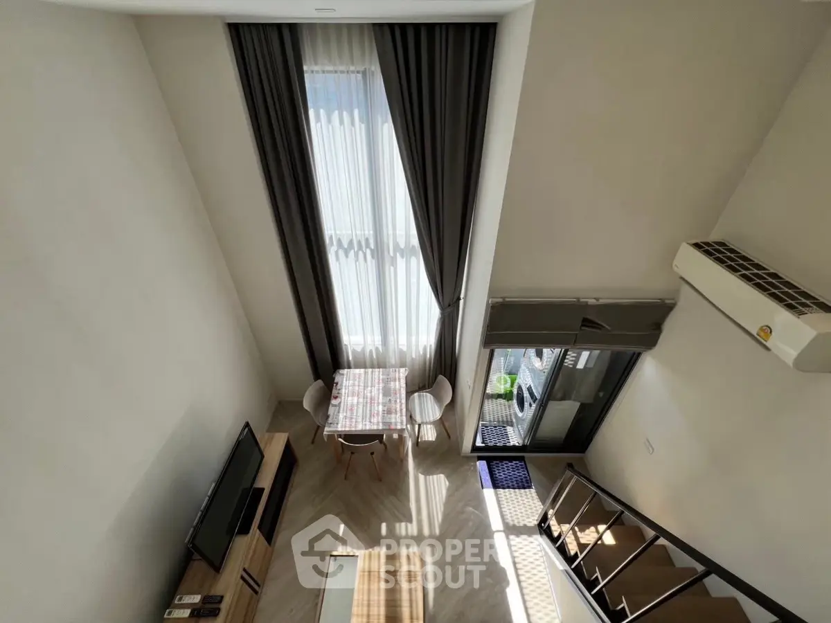 Modern loft apartment with high ceilings, large windows, and stylish decor, featuring a cozy dining area and balcony access.