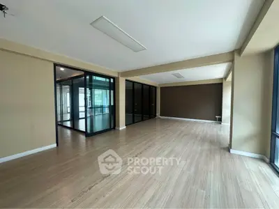 Spacious open-plan living area with large windows and wooden flooring.