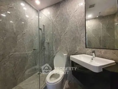 Luxurious modern bathroom with marble walls and glass shower enclosure.