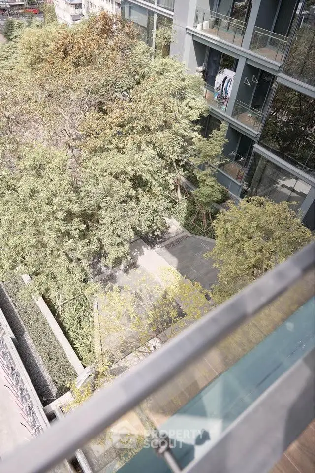 Modern building exterior with glass balconies and lush greenery view.