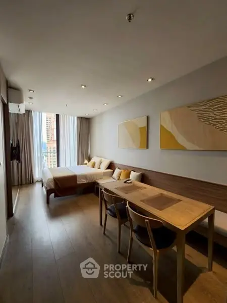 Modern studio apartment with stylish decor and large windows offering city views.