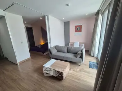 Modern living room with stylish sofa and wooden flooring, featuring a cozy ambiance and natural light.